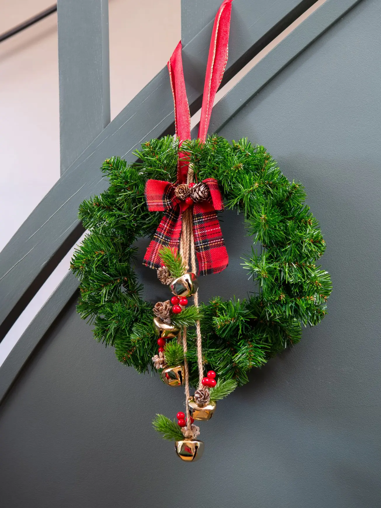 Couronne de Noël verte nouée d’un ruban tartan rouge