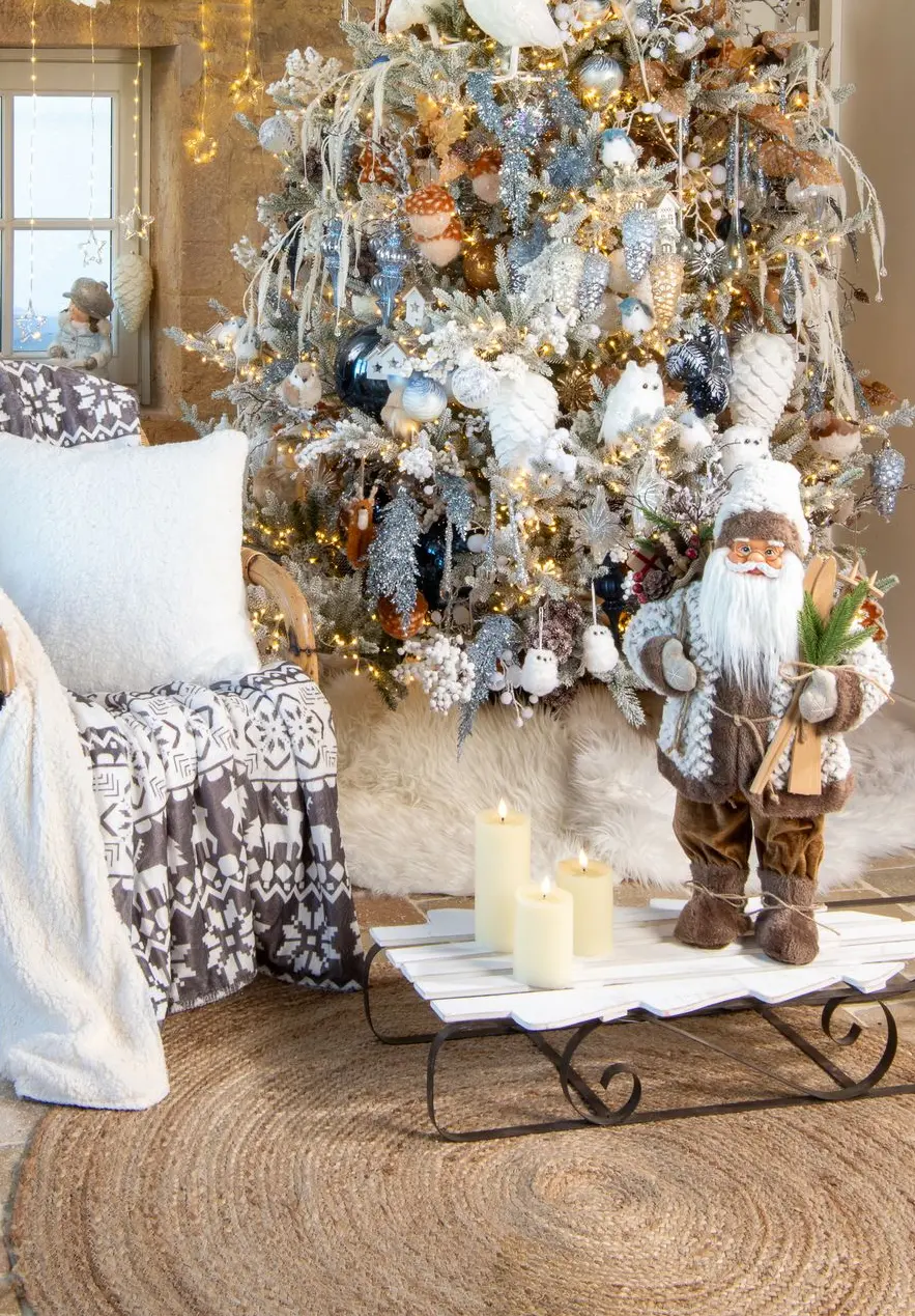 Sapin givré blanc et argent, fauteuil avec plaid, Père Noël et luge dans une maison en pierre