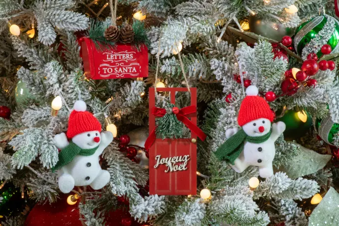Bonshommes de neige et décorations rouges dans un sapin floqué