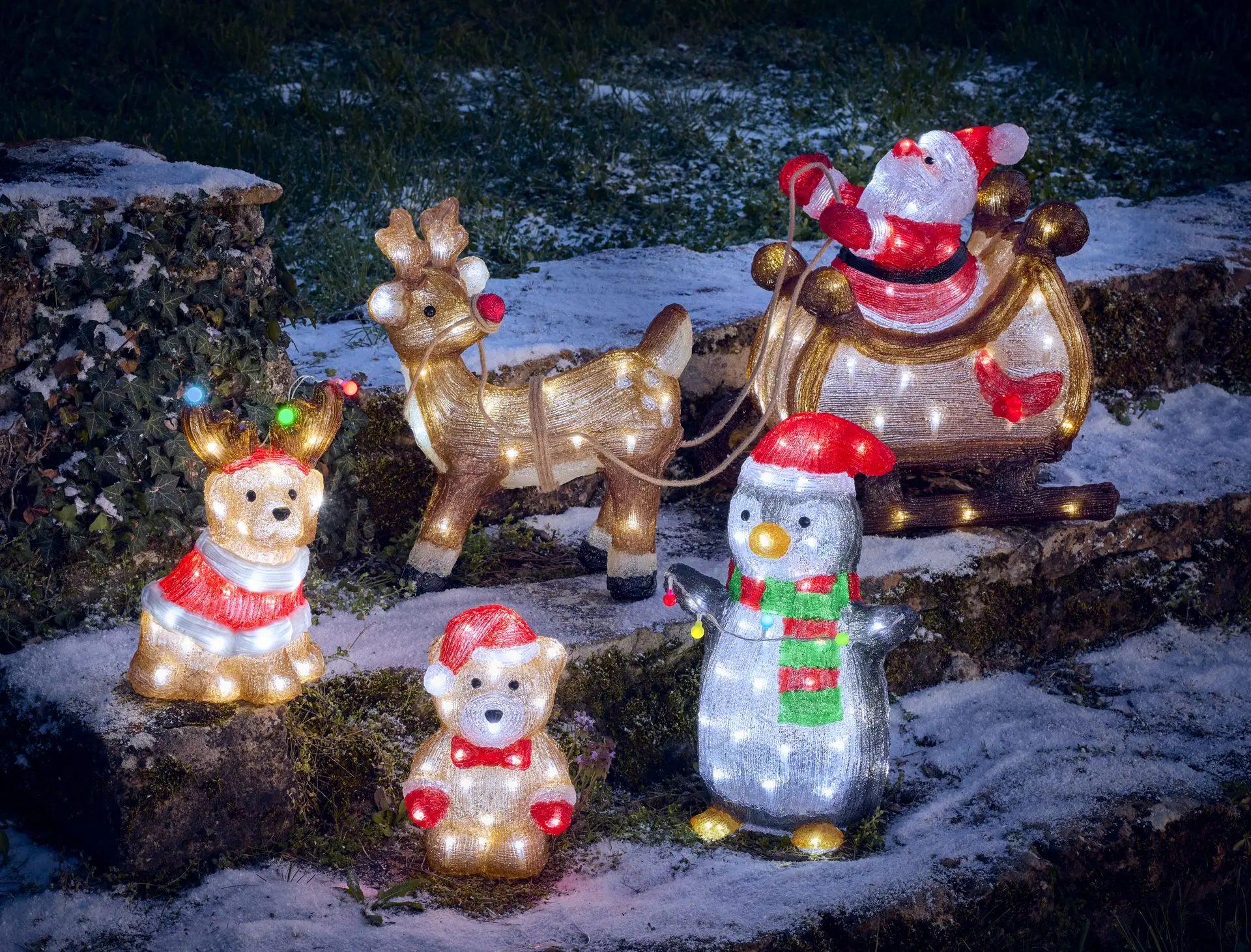Personnages lumineux de Noël installés dans un jardin enneigé